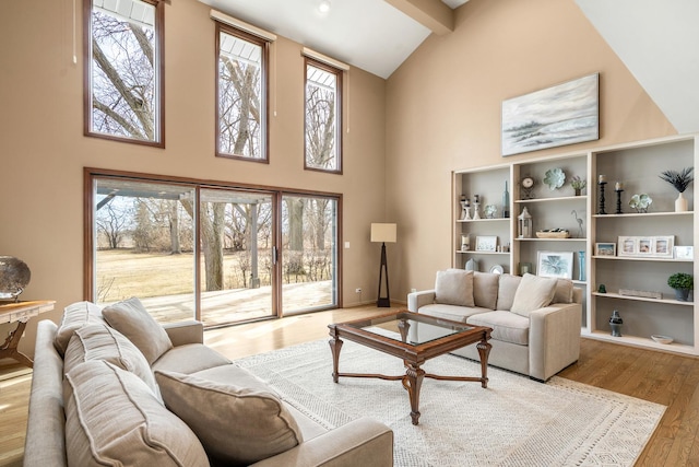 living room featuring beamed ceiling, high vaulted ceiling, baseboards, and wood finished floors