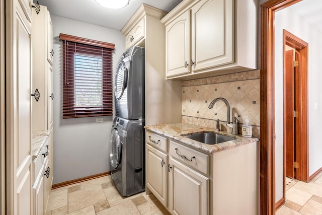 washroom featuring a sink, stacked washer / drying machine, cabinet space, and stone tile flooring