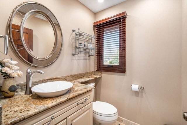 bathroom featuring toilet, vanity, and baseboards