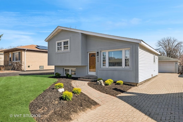 split level home with a garage, an outdoor structure, and a front lawn