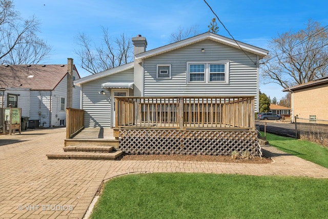 rear view of house with a wooden deck, fence, and a chimney