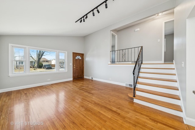 foyer featuring visible vents, lofted ceiling, stairway, wood-type flooring, and baseboards