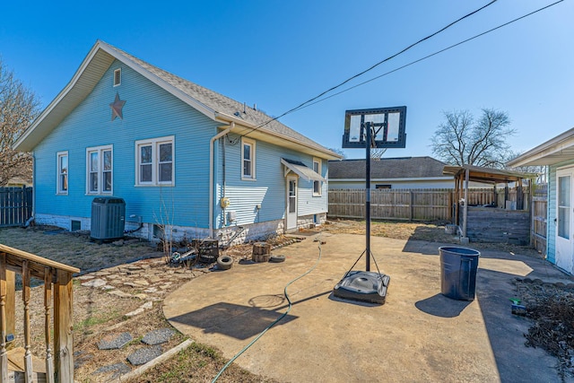 rear view of house with a patio, central AC unit, a fenced backyard, and a shingled roof