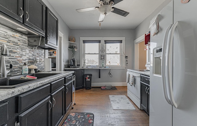 kitchen featuring white appliances, dark cabinets, and backsplash