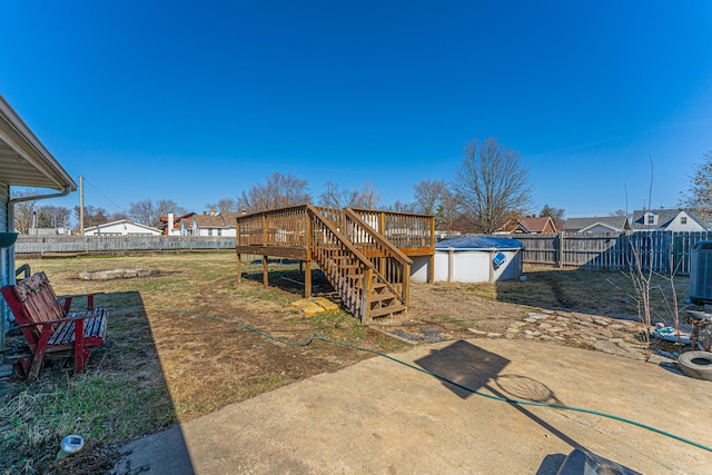 view of yard with a patio, an outbuilding, a wooden deck, a fenced backyard, and stairs