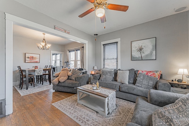 living area featuring ceiling fan with notable chandelier and wood-type flooring