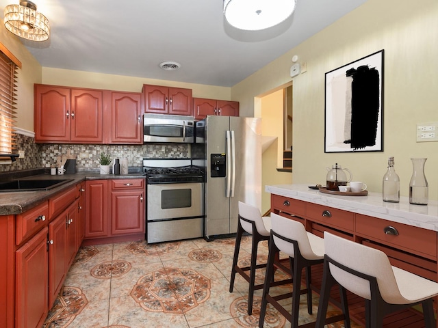 kitchen featuring light tile patterned floors, visible vents, a sink, appliances with stainless steel finishes, and tasteful backsplash