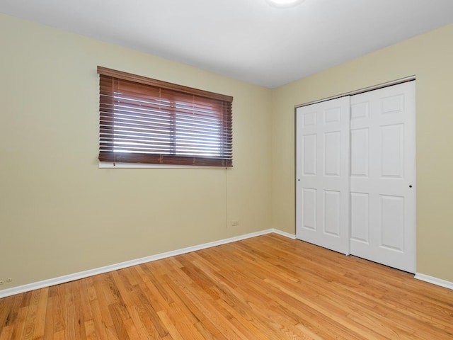 unfurnished bedroom with a closet, light wood-style flooring, and baseboards