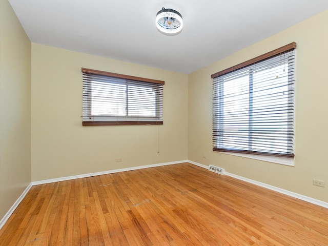 spare room featuring visible vents, light wood-type flooring, and baseboards