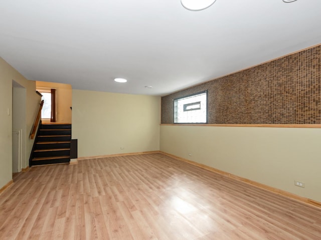 basement featuring stairs, baseboards, and wood finished floors