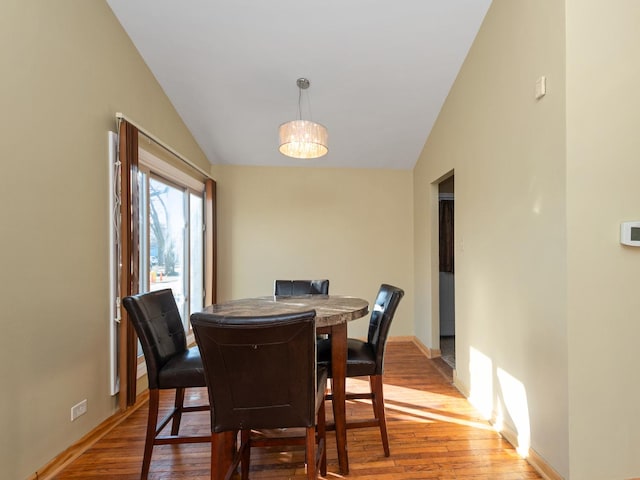 dining room with baseboards, wood finished floors, an inviting chandelier, and vaulted ceiling