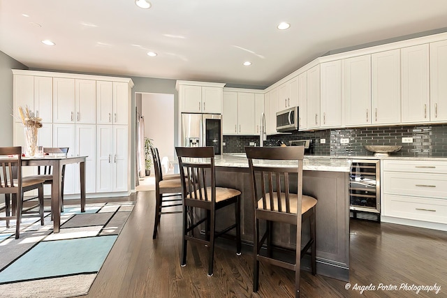 kitchen featuring dark wood finished floors, backsplash, white cabinetry, and stainless steel appliances