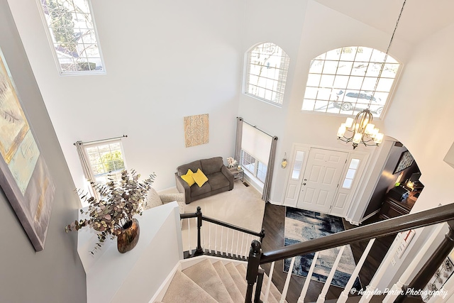 foyer entrance featuring stairway, a high ceiling, a notable chandelier, and wood finished floors