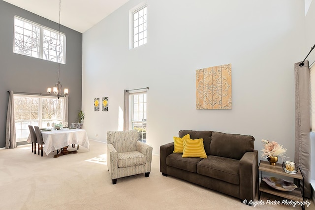 living area featuring baseboards, a notable chandelier, a towering ceiling, and carpet flooring