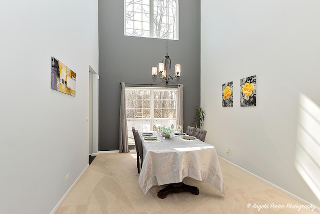 carpeted dining area featuring an inviting chandelier, baseboards, and a towering ceiling