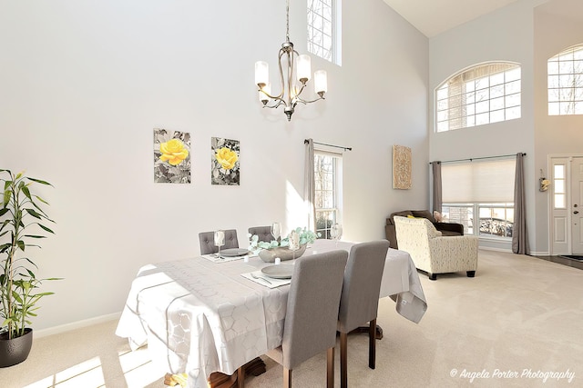 dining space featuring a chandelier, plenty of natural light, a towering ceiling, and carpet floors