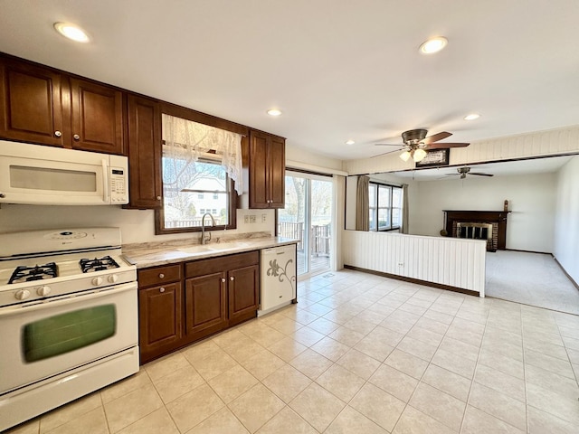 kitchen featuring white appliances, a fireplace, a sink, light countertops, and dark brown cabinets