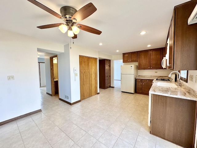 kitchen with baseboards, light stone countertops, recessed lighting, white appliances, and a sink