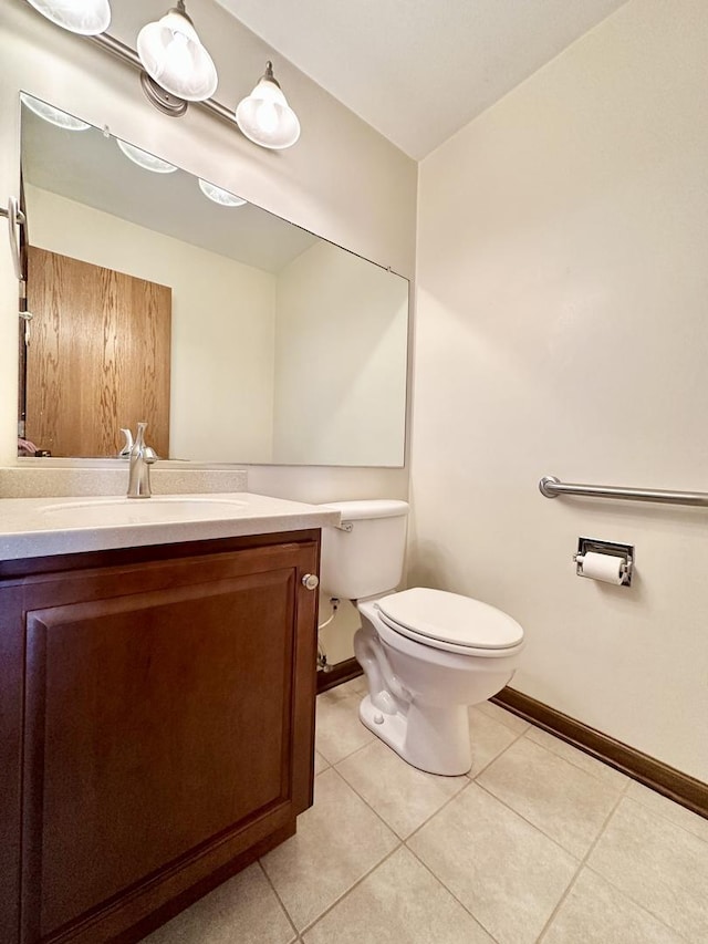 half bath with tile patterned floors, baseboards, toilet, and vanity