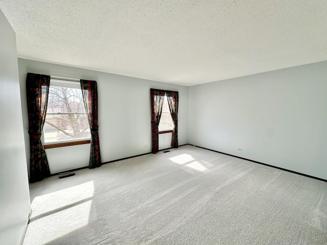 carpeted empty room with a healthy amount of sunlight, visible vents, and a textured ceiling