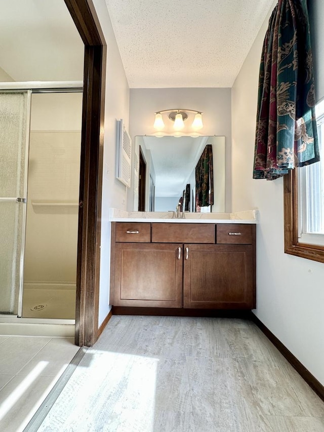 full bath featuring a stall shower, vanity, a textured ceiling, and wood finished floors