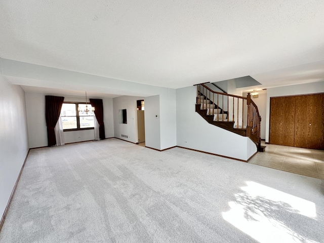 unfurnished living room with a notable chandelier, a textured ceiling, stairs, and carpet floors