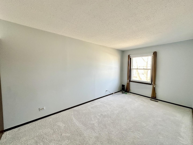 spare room with a textured ceiling, baseboards, visible vents, and light carpet