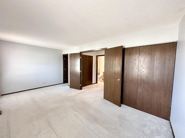 unfurnished bedroom with light colored carpet, baseboards, and a textured ceiling