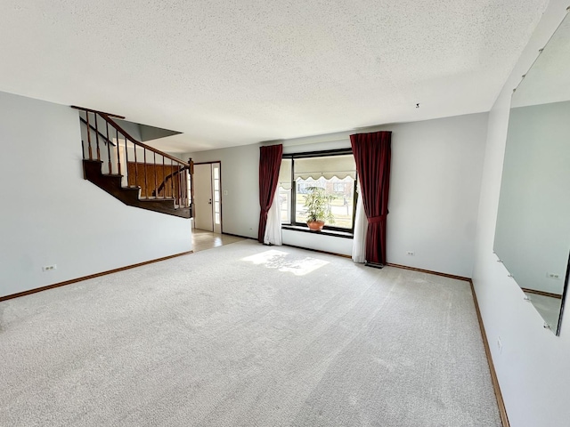 unfurnished living room with baseboards, light colored carpet, stairs, and a textured ceiling