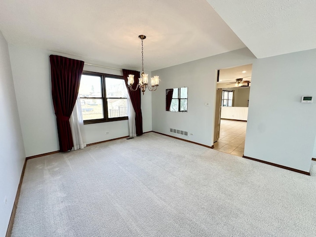 unfurnished room with ceiling fan with notable chandelier, light colored carpet, visible vents, and baseboards