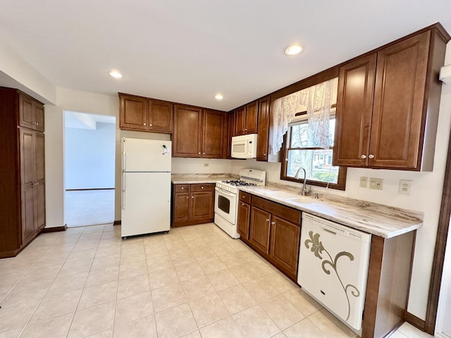 kitchen with recessed lighting, white appliances, baseboards, and a sink