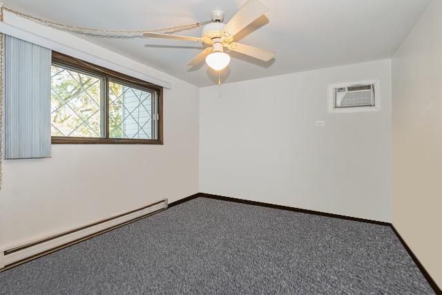 carpeted spare room with a baseboard heating unit, baseboards, a ceiling fan, and a wall mounted AC