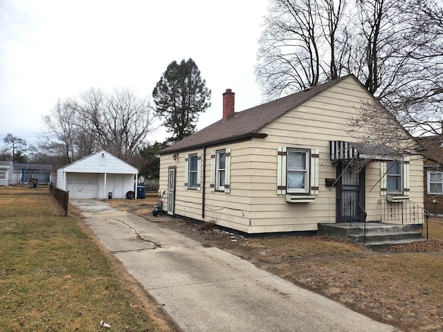 bungalow-style home with a chimney, a detached garage, an outdoor structure, and fence