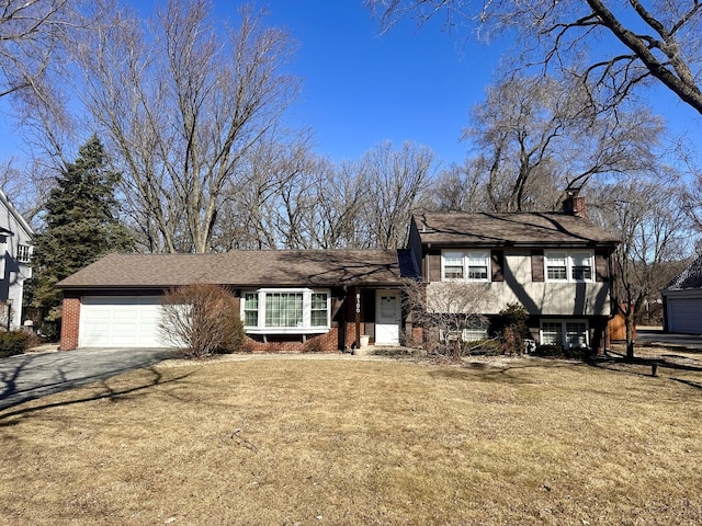 tri-level home featuring a front lawn, an attached garage, driveway, and a chimney