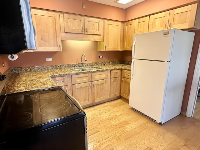 kitchen with light wood-style flooring, light brown cabinetry, a sink, black range with electric cooktop, and freestanding refrigerator