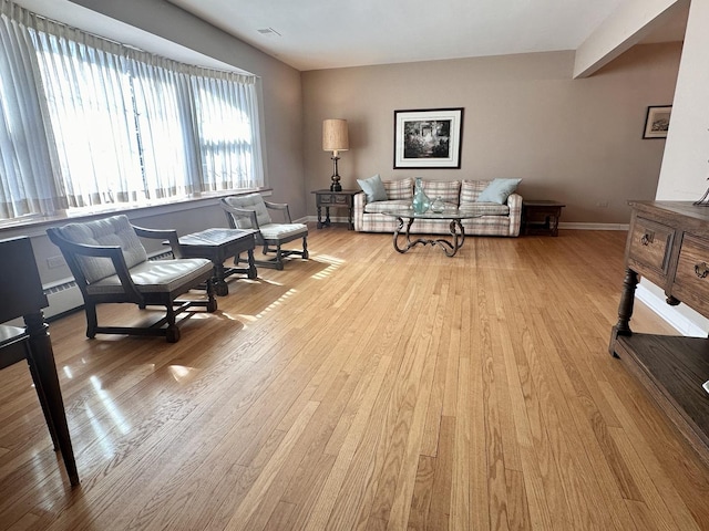 living area with visible vents, baseboards, and wood finished floors