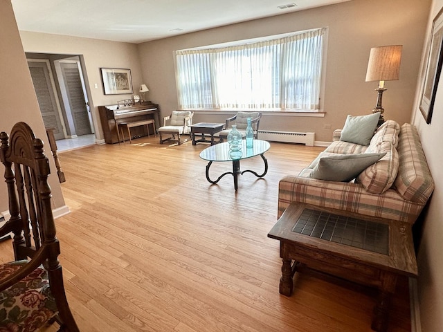 living area with visible vents, baseboards, a baseboard heating unit, and light wood-style floors