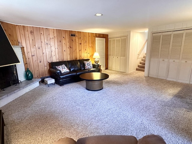 living room featuring stairs, visible vents, and carpet flooring