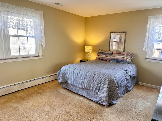 bedroom with a baseboard heating unit, multiple windows, carpet flooring, and visible vents