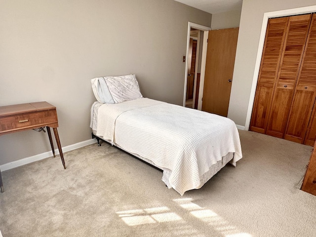 bedroom featuring light carpet, baseboards, and a closet