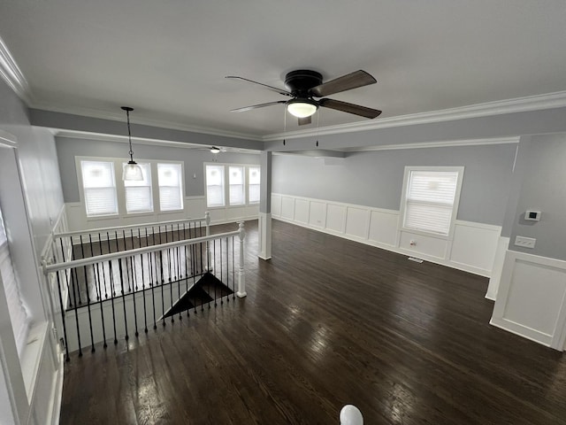 empty room featuring a wainscoted wall, dark wood-type flooring, and ornamental molding