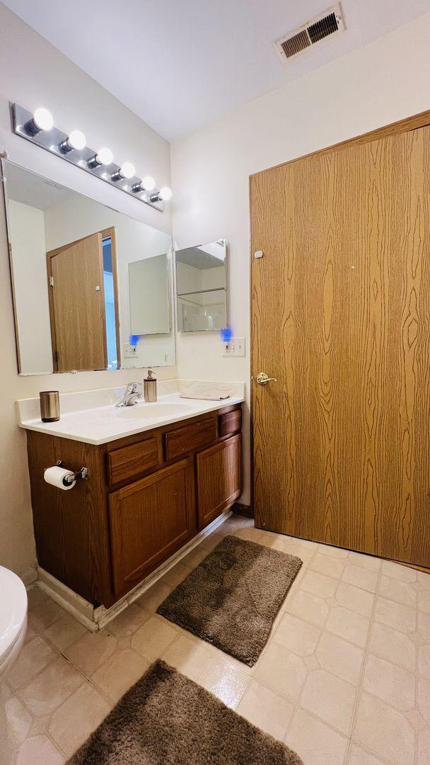 bathroom featuring visible vents, toilet, and vanity