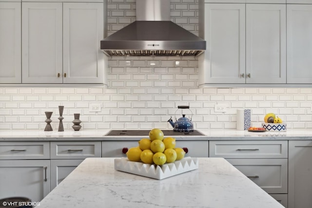 kitchen with tasteful backsplash, electric stovetop, white cabinetry, wall chimney range hood, and light stone countertops