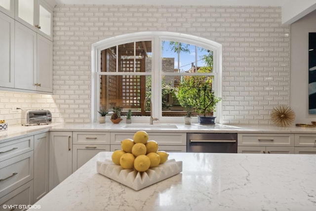 kitchen with white cabinetry, glass insert cabinets, tasteful backsplash, and a sink