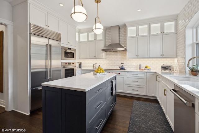 kitchen featuring a sink, stainless steel appliances, wall chimney exhaust hood, and white cabinetry