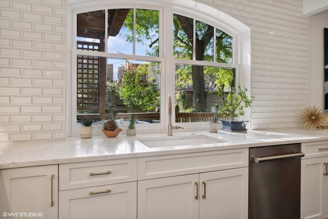 kitchen with a sink, decorative backsplash, light stone countertops, and white cabinetry