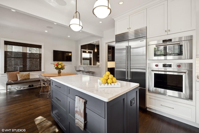 kitchen with light stone counters, dark wood-type flooring, appliances with stainless steel finishes, and gray cabinetry