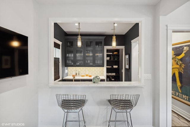 bar featuring decorative light fixtures, decorative backsplash, and baseboards