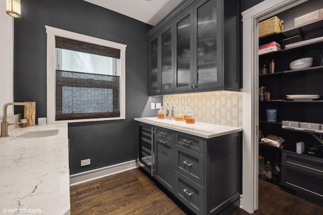 interior space featuring baseboards, visible vents, dark wood-style flooring, a sink, and wine cooler