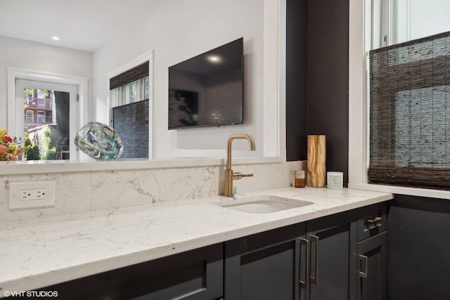 interior space with light stone counters, dark cabinets, and a sink